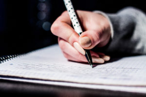 Person Writing on Notebook